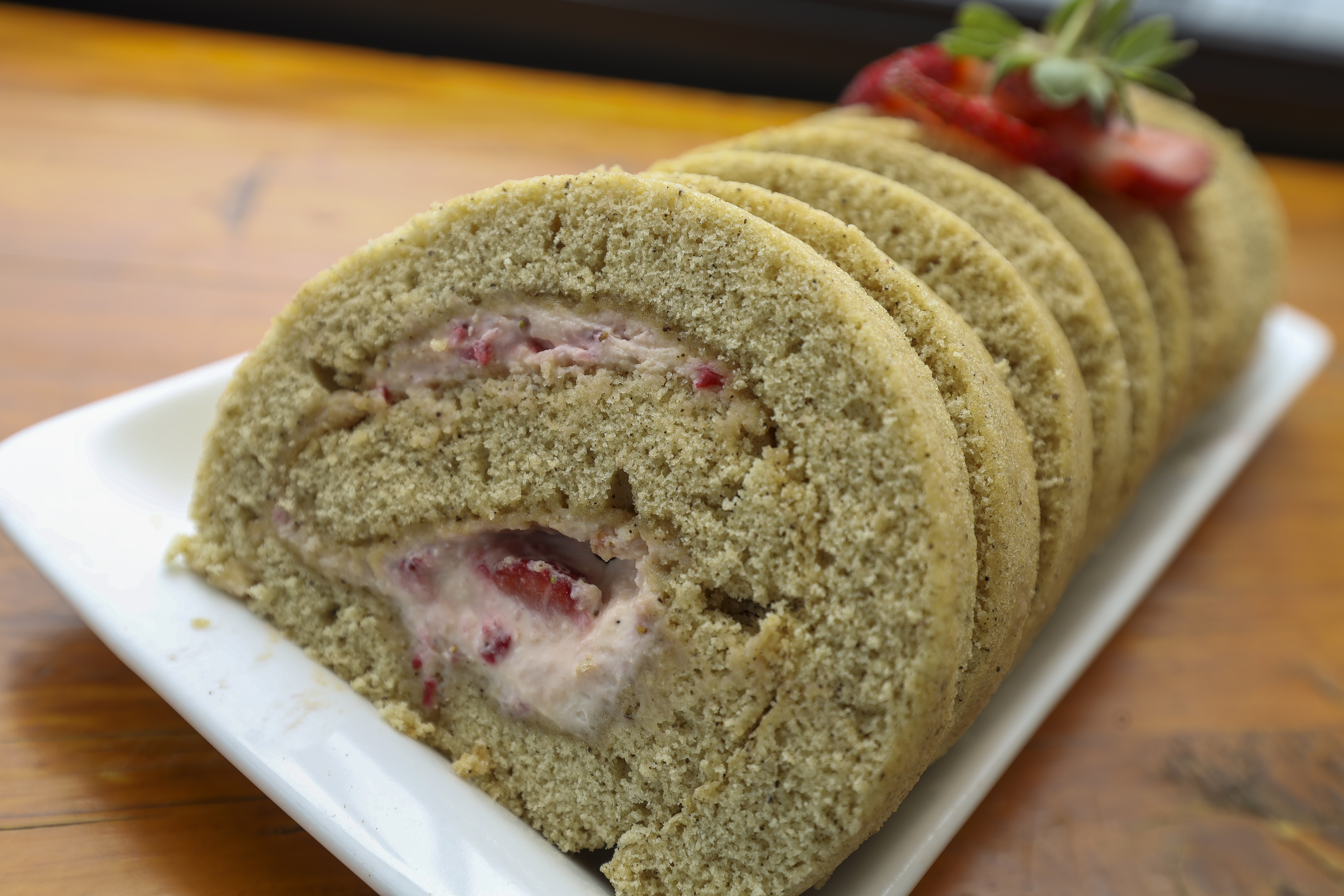 Green tea Swiss roll with strawberry cream, sliced and plated