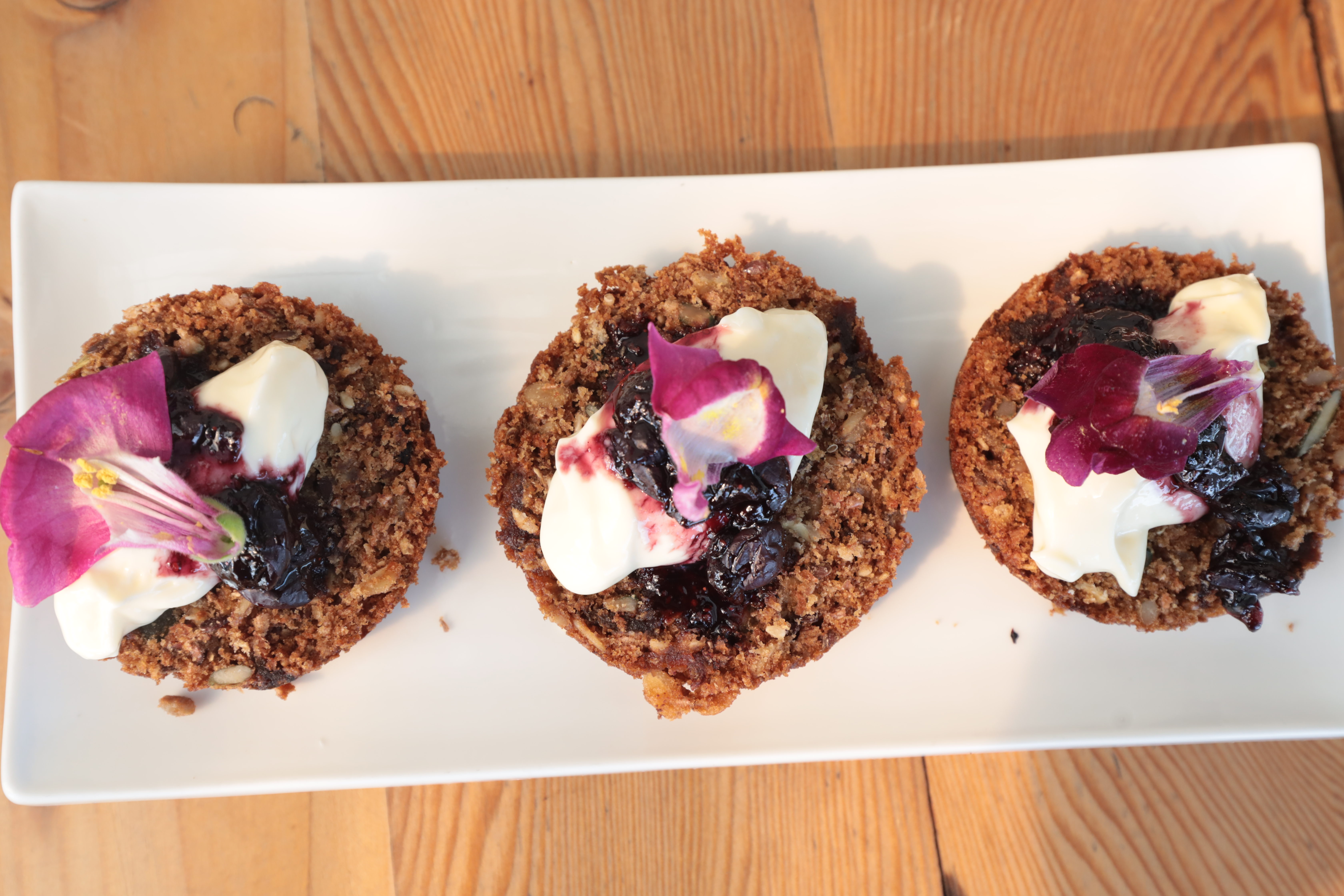 Three crumble desserts with cream and edible flower garnish